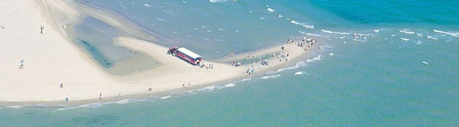 Tourists walking on the sandy tip where two seas meet at Skagen, Denmark.