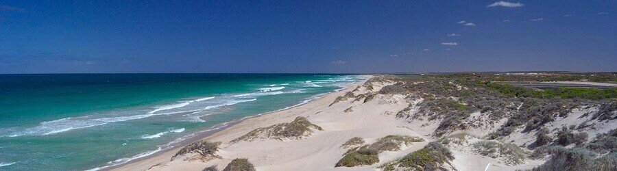Wide sandy beach with rolling dunes and deep blue water near Geraldton on Australia’s Coral Coast.