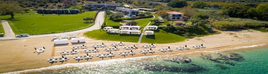 Komitsa Beach in Ouranoupoli, Greece with golden sand, sun loungers, and turquoise water.