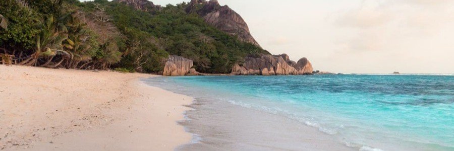 10 Most Beautiful Beaches | Anse Source d’Argent Anse Source d’Argent in the Seychelles with pale sand, turquoise water, tropical trees, and granite formations.