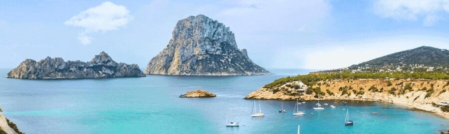 Es Vedra coastline in Ibiza with turquoise Mediterranean water sailboats and rocky island views
