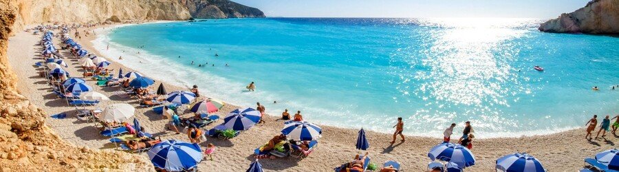 Pebble beach in Lefkada with blue umbrellas and bright turquoise water