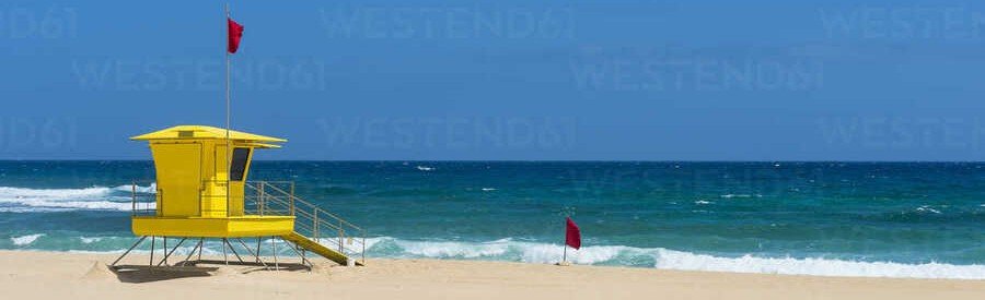 Fuerteventura Corralejo beach Spain with red flag and lifeguard tower on sandy shore