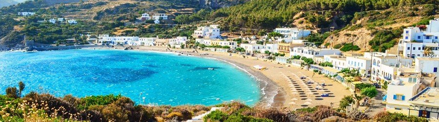Panoramic view of Diakofti Beach in Kythira, featuring turquoise water, a long sandy bay, and whitewashed houses along the shoreline.