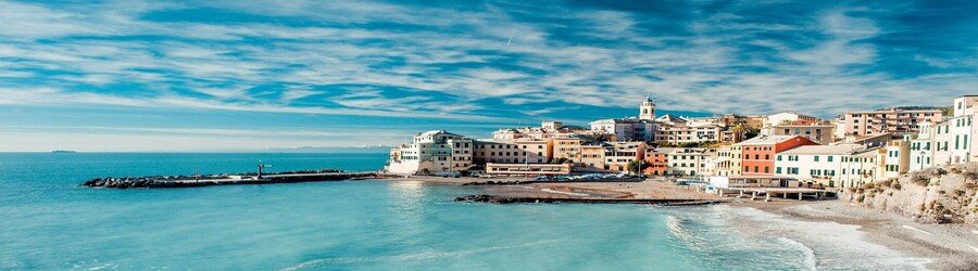 Colorful coastal buildings in Greece overlooking a calm blue sea and rocky shoreline