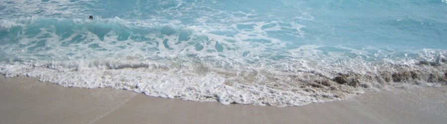 Gentle turquoise waves wash onto the soft sandy shore, creating a serene and relaxing beach scene.