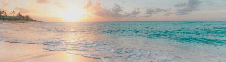 Sandy beach in Mexico at sunset with turquoise water, gentle waves, and soft golden light