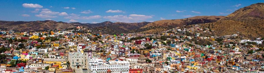 Colorful hillside townscape of Oaxaca Mexico surrounded by mountains.