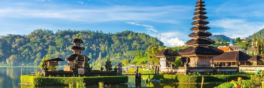 Ulun Danu Beratan Temple in Bali, with traditional tiered shrines reflected in a peaceful lake beneath lush green mountains.