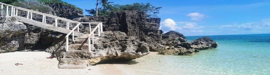 Hidden rocky cove on Bantayan Island with clear shallow water and stone steps leading to the beach