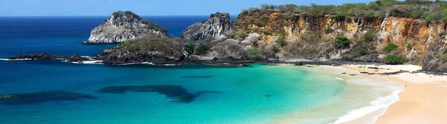 Tropical beach in Brazil with turquoise water, golden sand, and dramatic rocky coastline