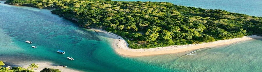Aerial view of Natadola Beach with soft white sand, turquoise water, and boats near the shore.