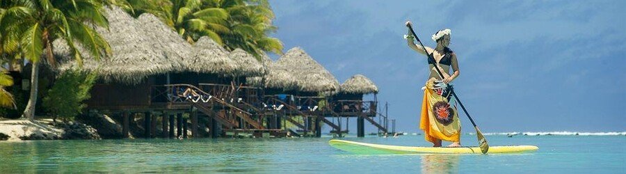Woman paddleboarding over clear turquoise water in Aitutaki, Cook Islands