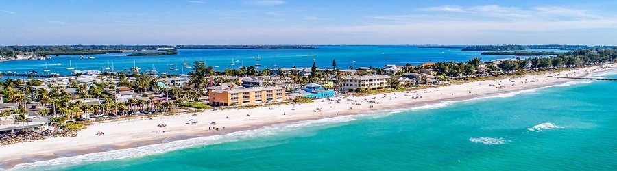 Beachfront view of Anna Maria Island Florida with turquoise waves and beach resorts.
