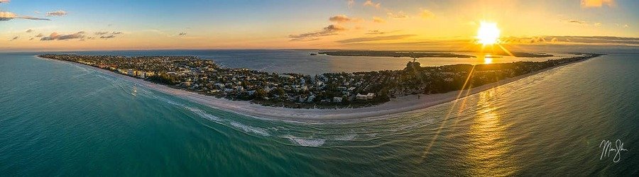 Aerial panorama of Anna Maria Island Florida at sunset with long stretches of beach and calm seas.