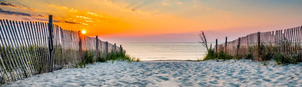 Sandy path to Siesta Key Beach at sunrise with soft golden light over the ocean.
