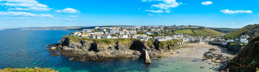 The picturesque fishing village of Port Isaac surrounded by cliffs and clear blue water in Cornwall UK.
