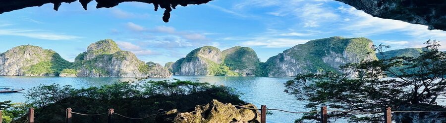 View of limestone cliffs rising from the sea, framed by a cave opening in northern Vietnam.