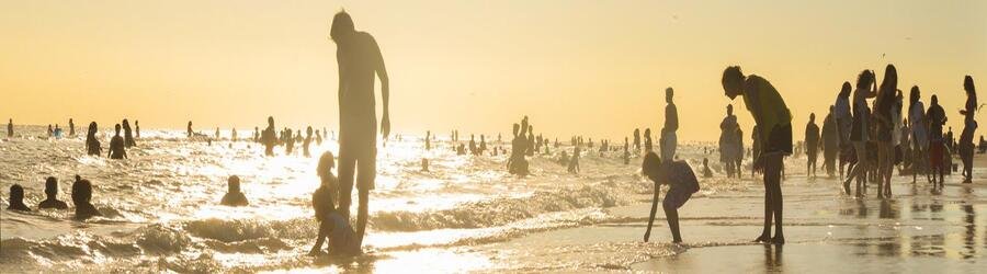 Families enjoying Siesta Beach at sunset with warm golden reflections on the water.