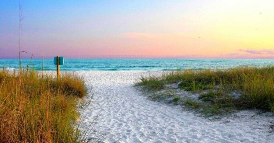 Pathway through sea grass leading to Siesta Key Beach at sunset with pastel skies and turquoise water.