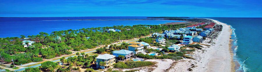 Scenic aerial of beach houses along St. George Island Florida with the Gulf of Mexico on one side and bay waters on the other.