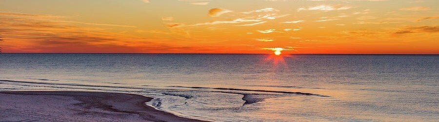Vibrant sunrise over the Gulf of Mexico as seen from St. George Island Florida with golden light reflecting off calm waters.