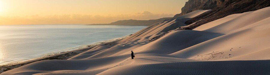 Golden sunrise over the Arher sand dunes on Socotra Island overlooking the calm Arabian Sea.
