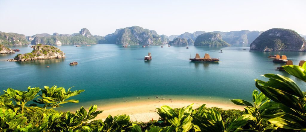 Boats sailing through emerald waters surrounded by limestone cliffs in Halong Bay, Vietnam.