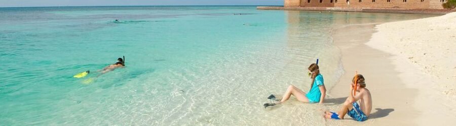Children snorkeling in shallow turquoise water near Fort Jefferson at Dry Tortugas National Park.