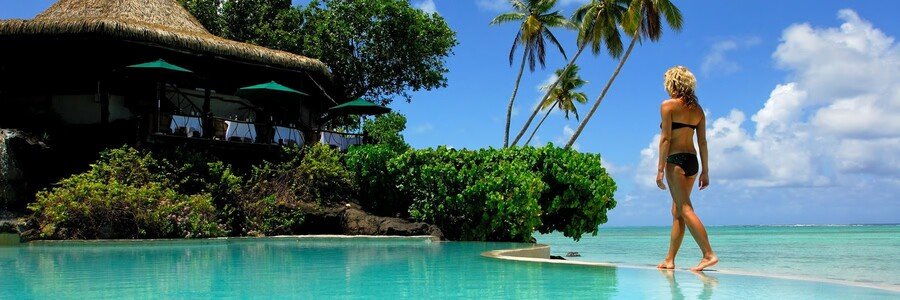 Pacific Resort Aitutaki lagoon pool and beachfront with palm trees in Aitutaki Lagoo