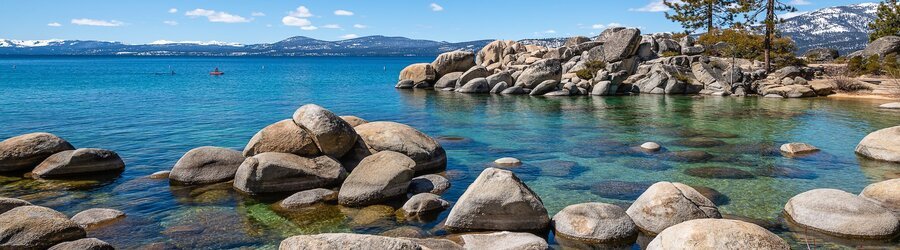 sand harbor rocky shoreline with clear turquoise water and lake tahoe mountains