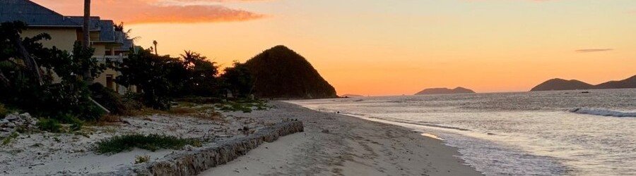 Orange sunset over a sandy beach and distant islands in Tortola