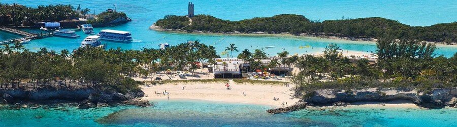 Aerial view of Blue Lagoon Island near Nassau with turquoise water, white sand beaches, palm trees, and excursion boats docked along the lagoon.