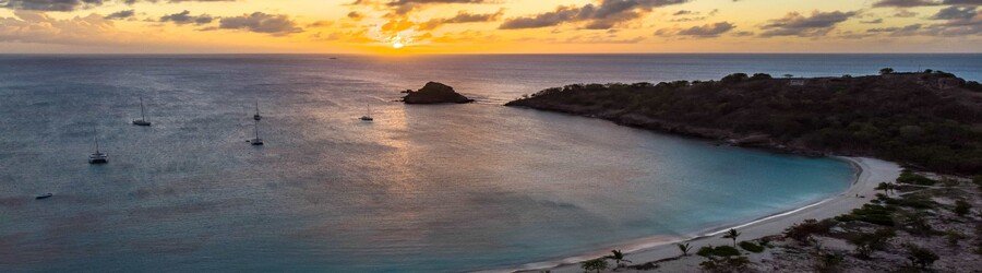 Deep Bay Antigua at sunset with calm turquoise water and anchored sailboats
Title: Deep Bay Antigua at Sunset