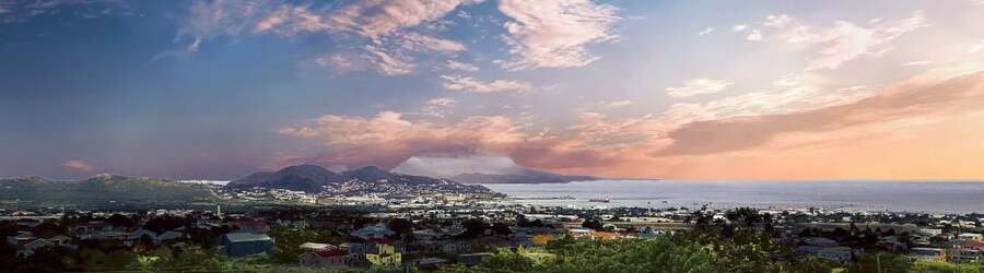 Panoramic sunset view over Basseterre, St. Kitts with city lights, mountains, and the Caribbean Sea.