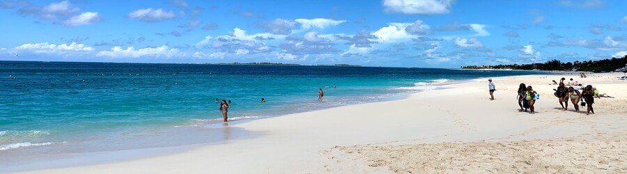 Visitors enjoying the wide, white-sand shoreline and turquoise water of Paradise Beach on Paradise Island.