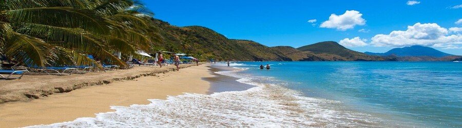 South Friars Bay Beach in St. Kitts with calm blue water, golden sand, and visitors relaxing along the shoreline.
