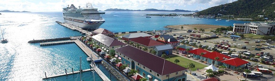 Aerial view of the Tortola Cruise Port in Road Town with a docked cruise ship, colorful waterfront buildings, and turquoise harbor water.