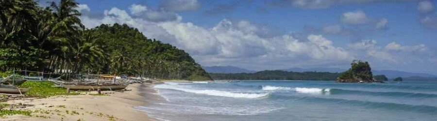 Long sandy beach in San Vicente Palawan with gentle waves, palm trees, and distant islands