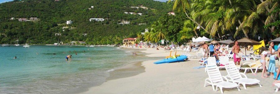 Beach chairs, swimmers, and calm water at Cane Garden Bay