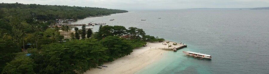 Coastline view of Samal Island with a sandy beach, pier, and calm blue water