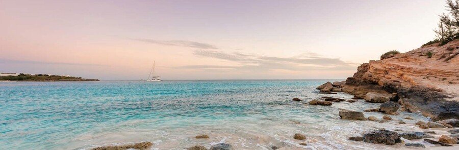 Sunset over a rocky shoreline in Phillipsburg St. Maarten with soft pastel skies and turquoise water