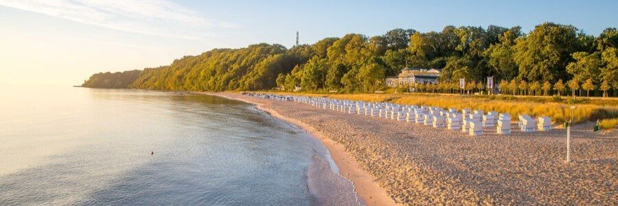 Nordstrand beach in Göhren Rügen Germany with strandkorb chairs along the Baltic Sea shoreline at sunset.