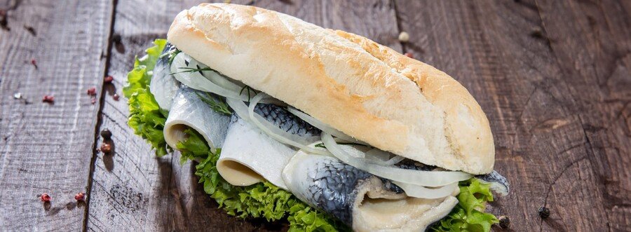 Traditional Fischbrötchen fish sandwich with herring onions and lettuce served on Rügen Island Germany Baltic coast