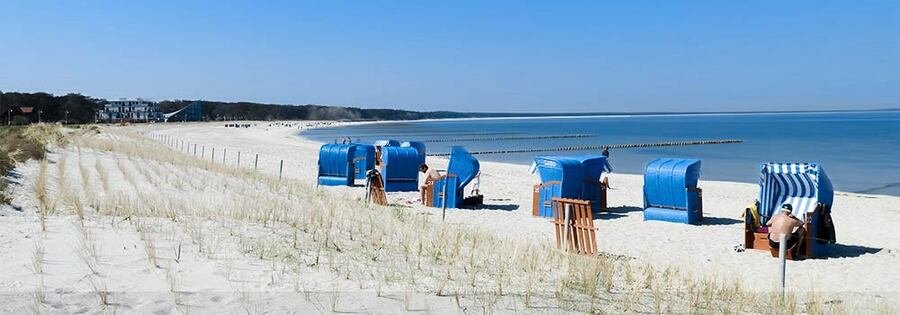 Sandy beach in Glowe on Rügen Island Germany with Baltic Sea shoreline and blue strandkorb beach chairs along the coast.