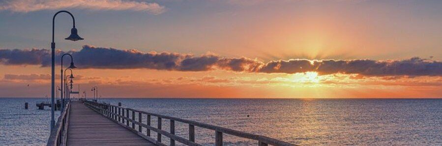 Göhren pier at sunset on Rügen Island with golden Baltic Sea horizon and wooden boardwalk.
