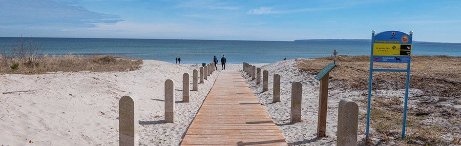 Wooden boardwalk leading to Juliusruh Beach on Rügen Island Germany with sandy dunes and Baltic Sea view.