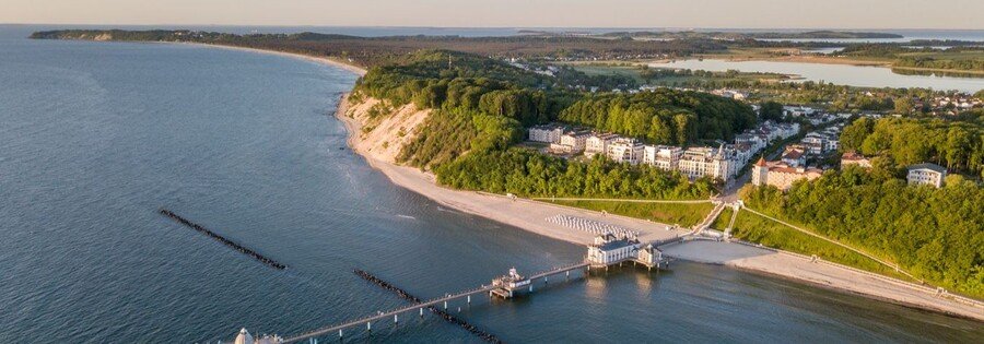 Aerial view of Sellin, Germany showing Baltic Sea coastline, sandy beach, historic Sellin Pier, and seaside hotels along the cliffs.