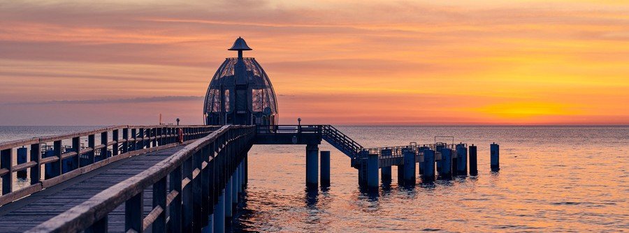 Sellin Pier on Rügen Island Germany at sunset with wooden walkway, Baltic Sea horizon, and glowing evening sky.