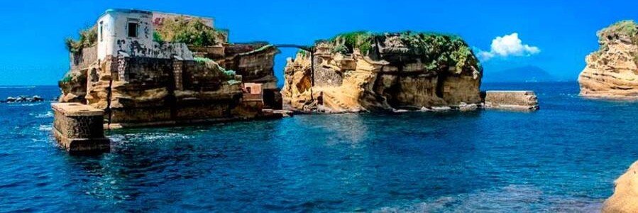 Small island and rocky coastline at Gaiola Beach with clear blue water in Naples Italy